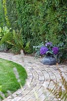 Curved brick path with shady planting of Ferns and Hosta - floral arrangement of Hydrangea and Eucalyptus
