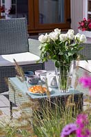 Lounge furniture set on patio - set for afternoon tea with cups, cakes and floral arrangement.
