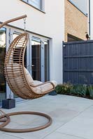 Hanging chair with cream cushions on patio. 