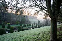 View down to the frozen lily pond, framed with clipped yews in the formal Canal Garden at Mapperton, Dorset.
