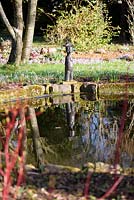 Statuette of naked female figure with hat beside the pond at The Down House, Hampshire in winter. 