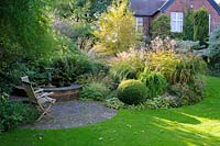 MIxed green foliage planting  and circular pond in garden - Shropshire, UK
