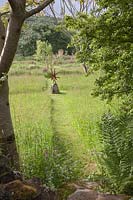 Metal sculpture of Acrobats 'Head over Heels' beside grassy path at Dyffryn Fernant, UK