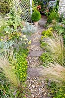  Gravel and stone pathway winding through prairie style planting.