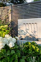Grey painted fence and zinc water fountain  with Hydrangea Annabelle