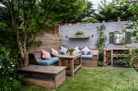 Small courtyard garden in West London with artificial lawn, built in Reclaimed 
Scaffold board seating and dining area with brick barbecue  
Garden designed by James Walsh.