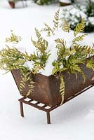 Old rusted container with snow covered ferns