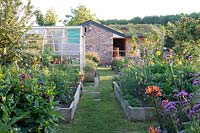 Kitchen garden with rasied beds planted with vegetables and flowers for cutting greenhouse and adjacent paddock with stable  â€‰  â€‰