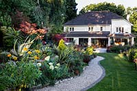 Mixed planted borders with house - Pam Woodall's garden, 'Pinecombe' in Dorset, UK