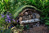 Wildlife garden with bug chalet surrounded by pine cones - Pam Woodall's garden, 'Pinecombe' in Dorset, UK