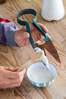 Applying the bicorbonate of soda paste to the topiary shears using a wooden spatula