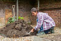 Removing soil from edge of raised bed to ensure a level base