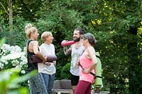 4 people are talking in a garden after a yoga course.