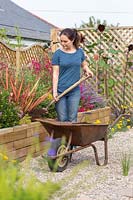 Woman adding soil improver to raised bed using a space