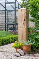 Wooden post in garden as finale for hedge