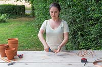 Woman is cutting lengths of copper wire with snippers