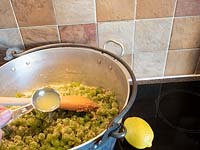Adding lemon juice to jam pan full of harvested green grapes and sugar