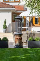 View across lawn to patio area  with patio heater and house. 