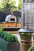 View past formal planters and patio heater to outdoor pizza oven.
