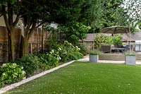 Large garden in St John's Wood with artificial lawn and raised deck seating area 
