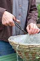 Person cutting plastic liner in hanging basket to ensure good drainage