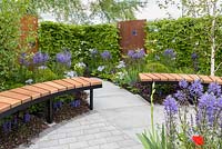 Carpinus betulus hedge, steel panels and  circular bench with flowering borders. 'Memories of Service' RAF 100 Appeal, RHS Malvern Spring Festival, 2018.