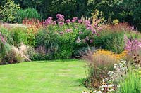 View of curved, flowering, perennial beds cut into lawn. 