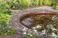 Path with porphyry setts and water-feature with Amni visnaga. 'Health and Wellbeing Garden', RHS Hampton Flower Show 2018