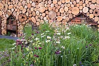Log wall with insect hotel. 'Family Garden', RHS Hampton Flower Show, 2018