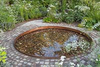 Circular pebble pool surrounded by a brick path, 'Health and Wellbeing Garden' RHS Hampton Flower Show, 2018. 