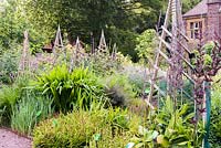 View of flowerbeds and wooden obelisks to support climbers.  University of Bristol Botanic Garden, Bristol, UK