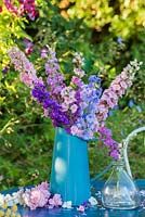 Delphinium consolida - Larkspur - displayed in pottery jug on garden table.
