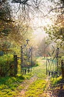 Gate by Dave Bissell with dragonflies and bulrushes. Moors Meadow Garden and Nursery, Bromyard, Herefordshire, UK