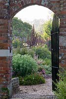 View through gate into walled garden and along double herbaceous borders at Edmondsham House, Cranborne, Wimborne Minster, Dorset, UK