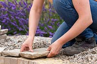 Woman placing pavers at edge of firepit.
