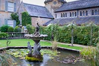 Decorative pond with fountain and Romanesque chapel behind. 