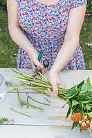 Woman using secateurs to cut the ends of the flowers to ensure an even length. 