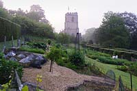 Formal vegetable garden with backdrop of the tower of St Mary the Virgin, Netherbury, UK. 
