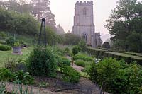 Formal vegetable garden with backdrop of the tower of St Mary the Virgin, Netherbury, UK.