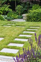 Rectangular, granite stepping stones lead across the lawn to a sunken, shady terrace at the rear of the garden.