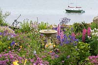 Sundial immersed in flowering perennials and annuals in seaside front garden.