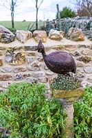 Decorative metal guinea fowl on a sempervivum encrusted stone plinth