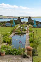 Running down the centre of this coastal garden is an 18-metre-long rill edged in flag irises, alchemilla, libertia, allium and phalaris.