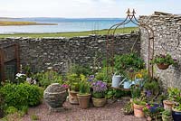 Tall dry stone wall wards off sea breezes from a small courtyard. 