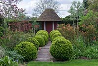 Rows of topiary Buxus balls alongside a path leading to a small summerhouse.