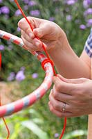 Woman yying a knot by each hula hoop layer to avoid the hoops moving up or down. 
