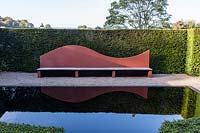 Wave form seat in Reflecting pool with Taxus baccata - Yew hedge at Veddw House Garden, Monmouthshire, Wales