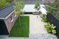 Overview of small patio garden with gravelled area and benches. 