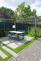 View of patio, with modern garden furniture and wooden pergola. 