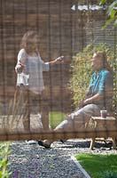 View of women chatting in garden through wicker screen.